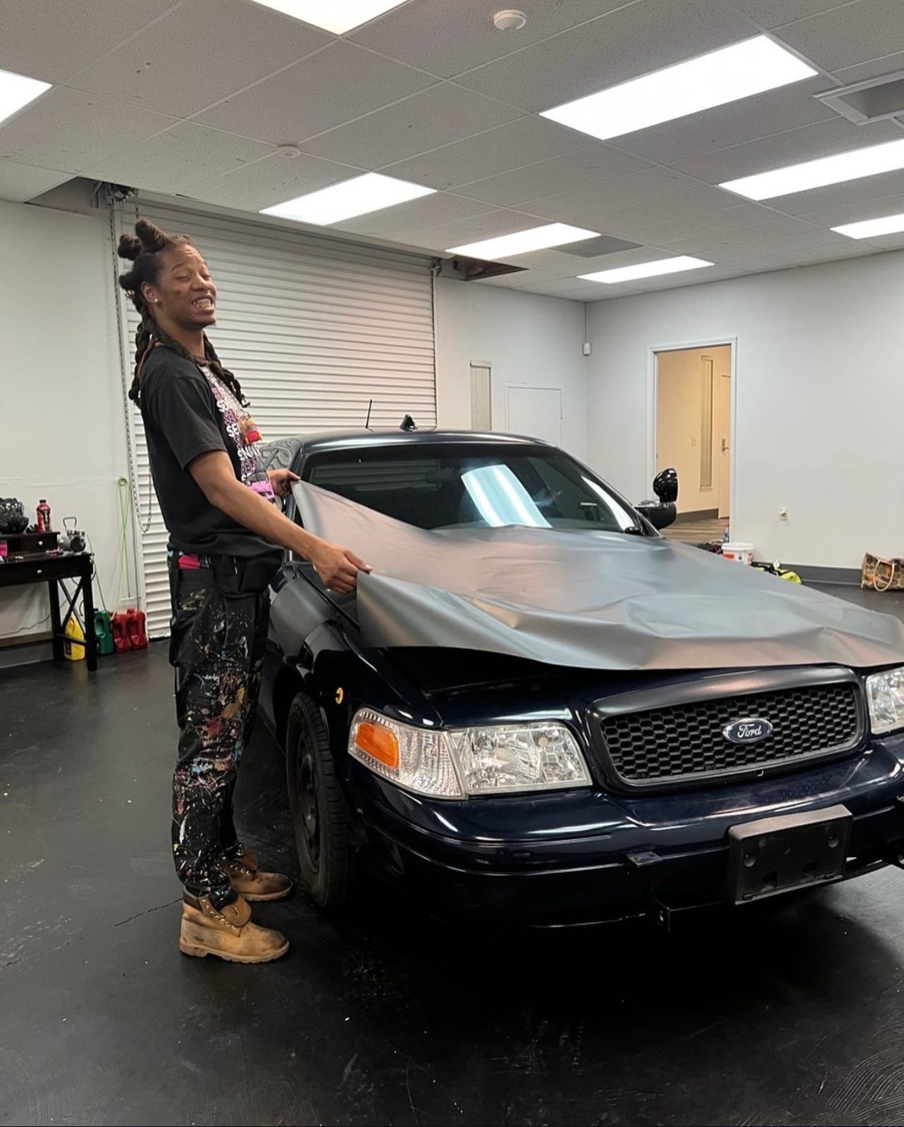 Installer laying wrap film across a sedan hood